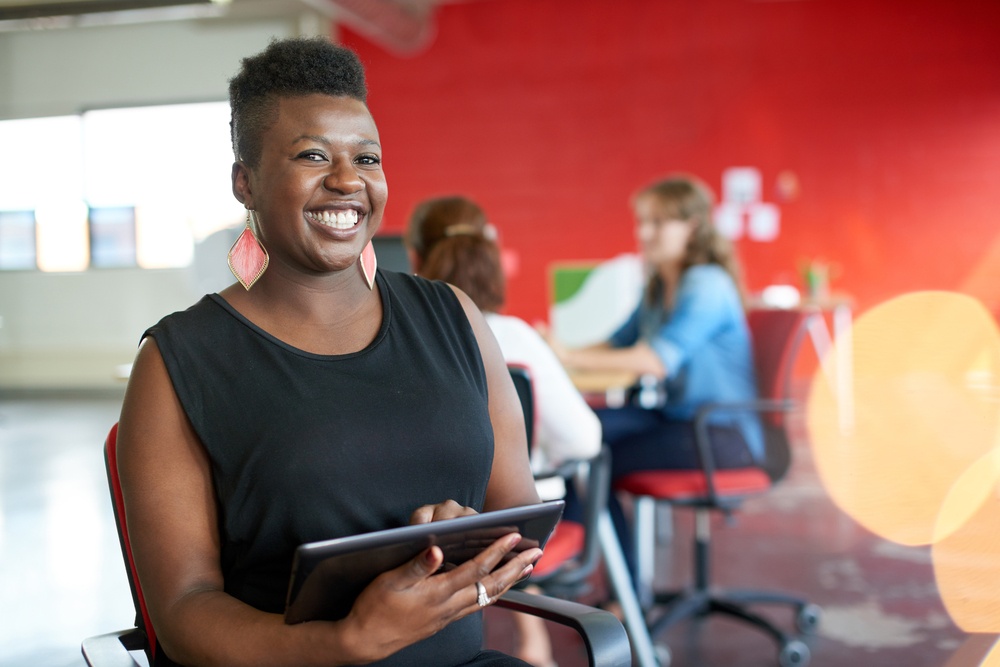 Confident female designer working on a digital tablet in red creative office space.jpeg